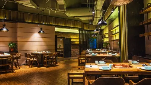 Modern restaurant interior with warm, dim lighting and wooden dining tables